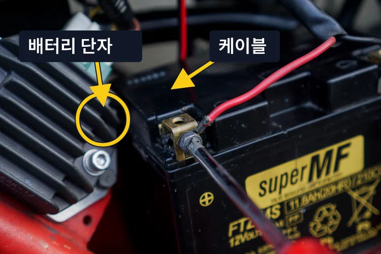 오토바이 배터리 단자와 케이블의 체결 상태를 확인하는 모습